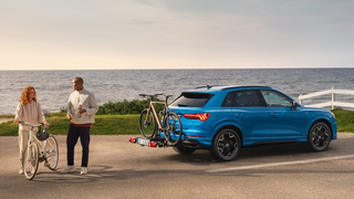 Pärchen lädt seine Räder vor einem Ausflug von ihrem Audi Fahrradheckträger